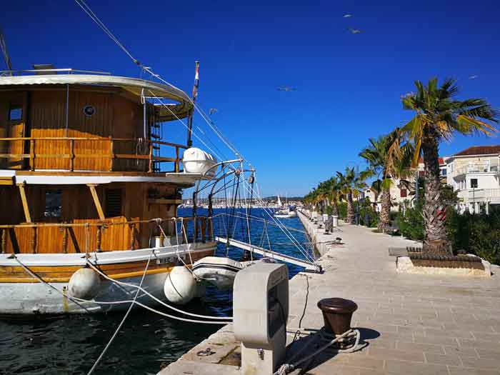 Wooden boat at the quay among palm trees